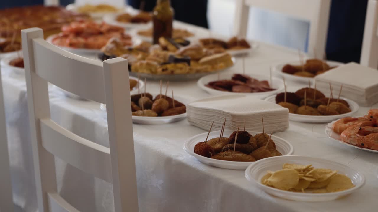 Tavolo da pranzo preparato con piatti di antipasti, gamberetti, stuzzichini fritti e dolci per un pasto a buffet o una celebrazione.