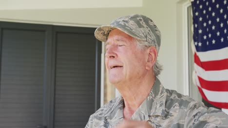 video of happy caucasian senior soldier wearing uniform standing outside house