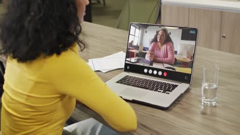 Mujer-Birracial-Usando-Una-Computadora-Portátil-Para-Videollamada,-Con-Un-Colega-De-Negocios-En-La-Pantalla