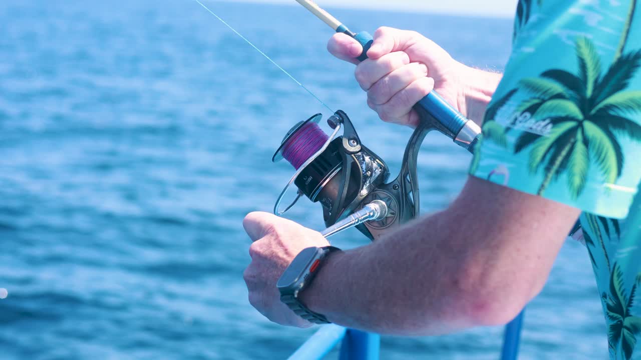Un uomo con una camicia tropicale pesca da una barca a Phuket, Thailandia, sotto la luce del giorno intensa