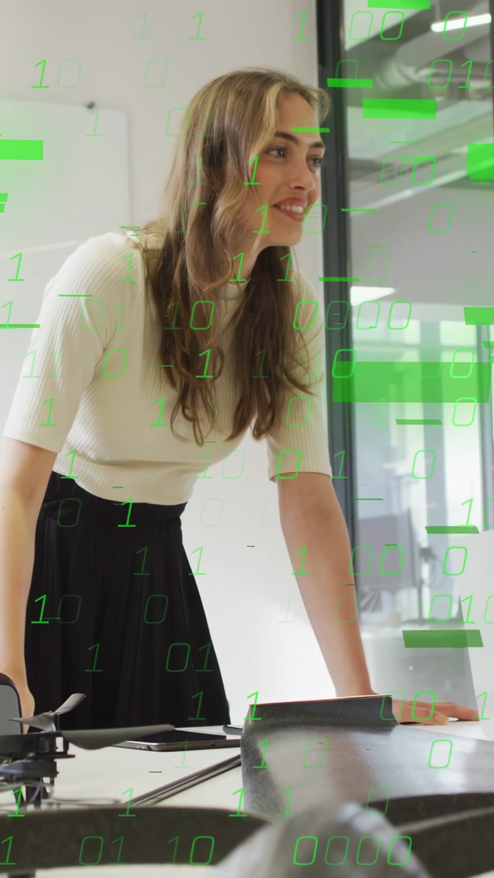 Video verticale: Donna che conduce un meeting tecnologico con laptop, drone, collega che indica, con un overlay verde che sale.