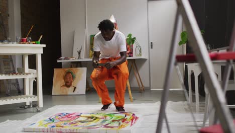 african american male artist taking a picture of his painting with a smartphone at art studio