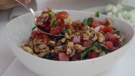 una ensalada de tomates picados, nueces, perejil y cebollas