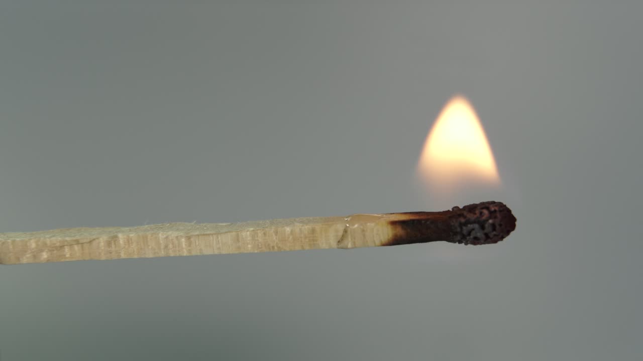 fósforo encendido, palo de madera ardiendo lentamente y cenizas negras encogiéndose, tiro macro conceptual