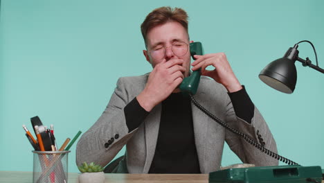 Tired-bored-business-man-talking-on-wired-vintage-telephone-of-90s,-fooling,-making-silly-faces