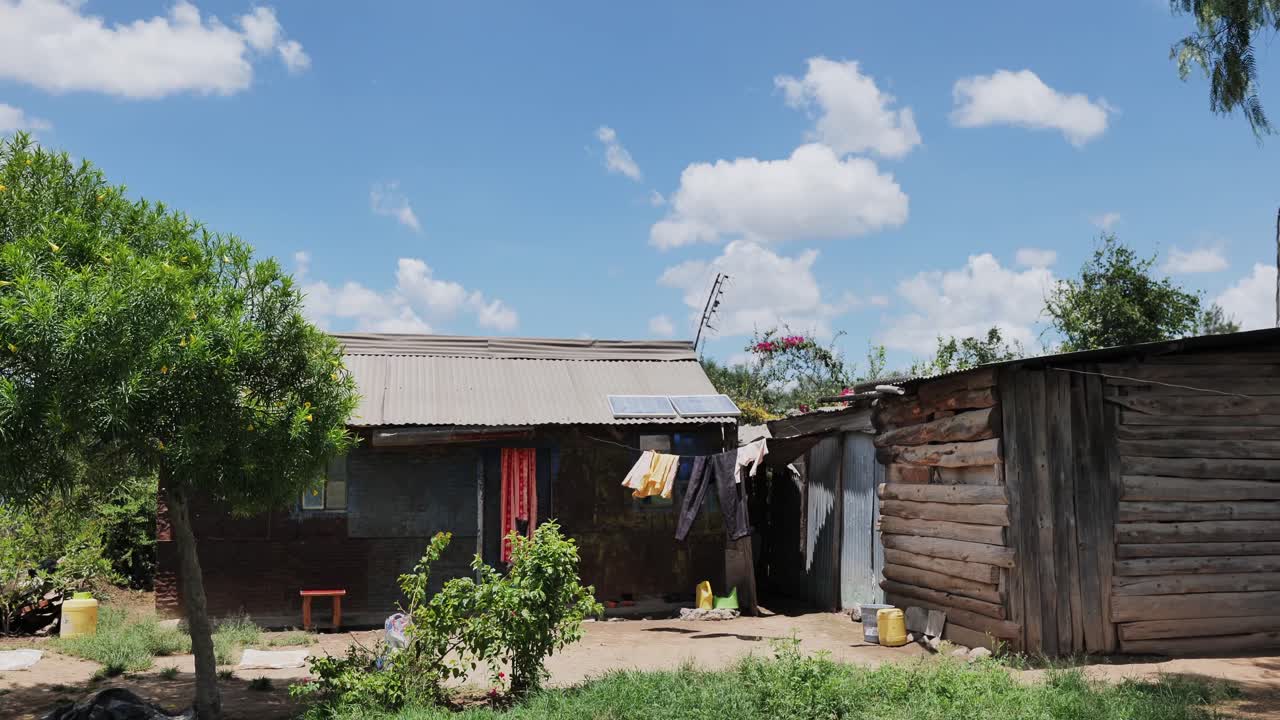 A modest rural dwelling with wooden and metal structures is set in Africa