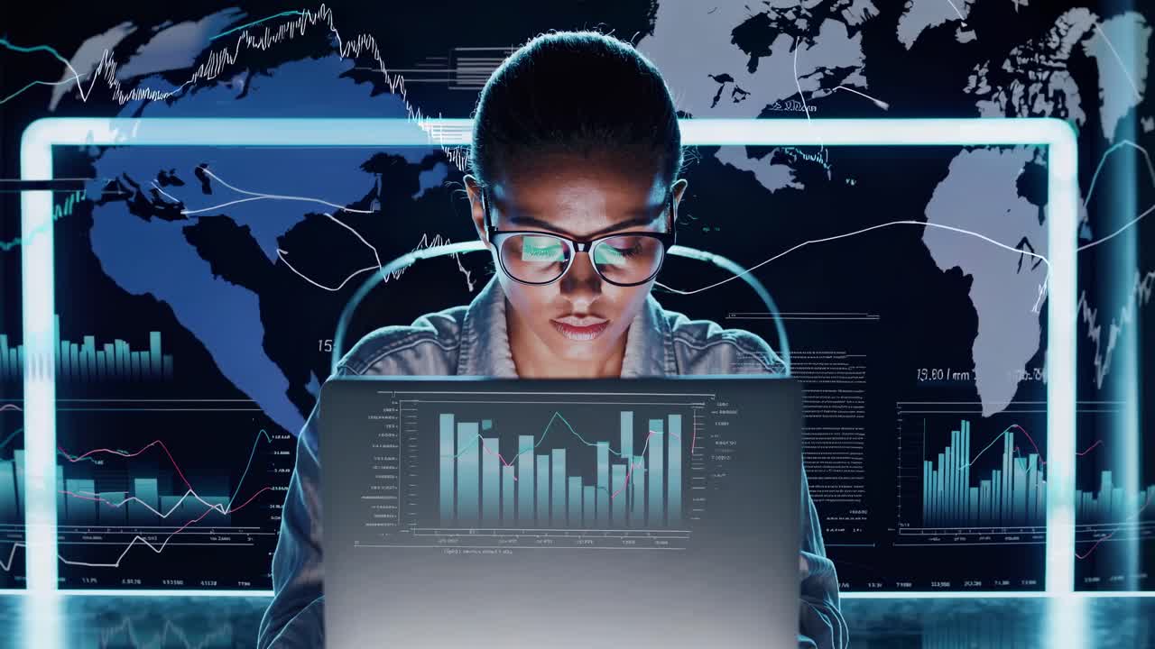 A focused individual works on a laptop with financial graphs in the background