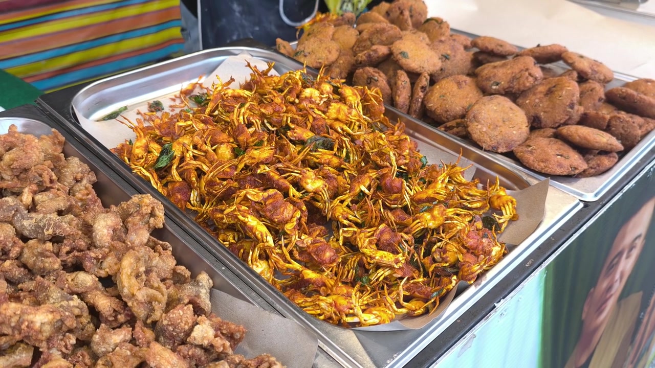 Kepiting bayi goreng renyah dilapisi tepung berbumbu disajikan di atas nampan. Camilan jajanan kaki lima Asia yang populer siap dijual di lapak pasar lokal. Hidangan laut gurih yang lezat