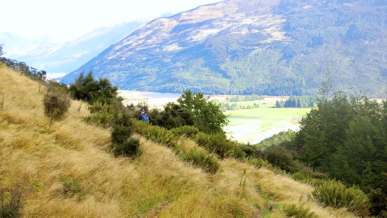 A serene hike along a grassy trail with mountain views in New Zealand, captured in bright daylight
