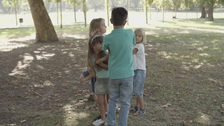 Crianças felizes de pé, de mãos dadas e brincando no parque