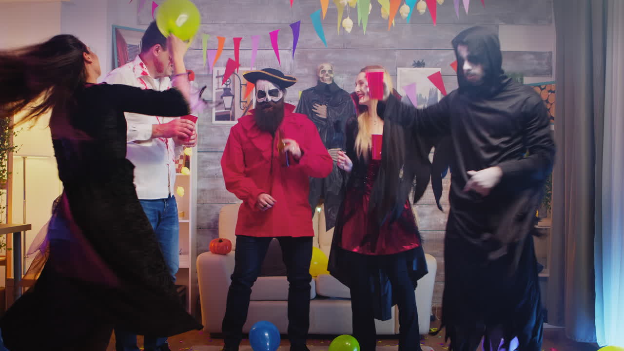 Group of people dancing and having fun at Halloween party in a decorated house
