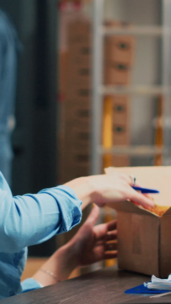 Vídeo vertical: mujer emprendedora que mira mercancía en cajas para planificar el envío de productos