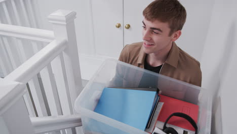 Estudiante-Universitario-Varón-Llevando-Una-Caja-Por-Las-Escaleras-Moviéndose-Hacia-El-Alojamiento