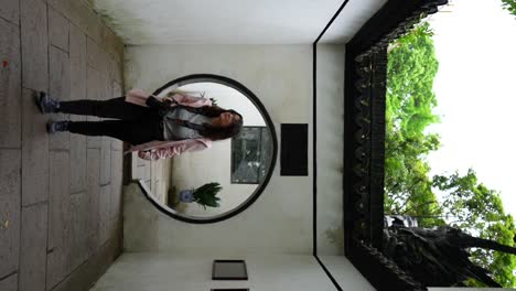 Female-traveler-walks-through-circular-doorway-at-Yu-Garden-in-Shanghai,-China