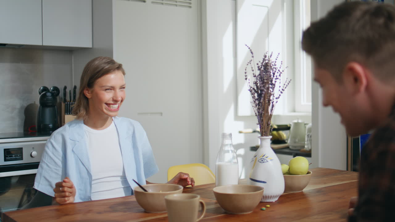 Joyful wife playing husband during home breakfast. Happy married couple having
