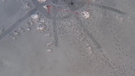 red warning tape around triangle shaped ice hole on frozen lake