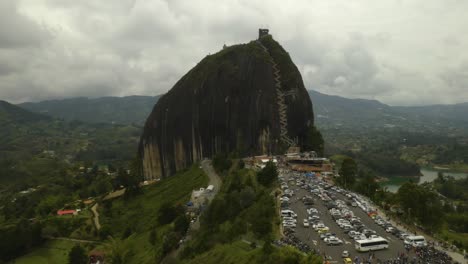 drone vuela lejos de la piedra del penol, con estacionamiento lleno de turistas