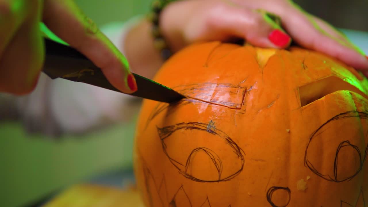 un primerísimo plano de la calabaza tallada con cuchillo para halloween con una luz espeluznante en el fondo