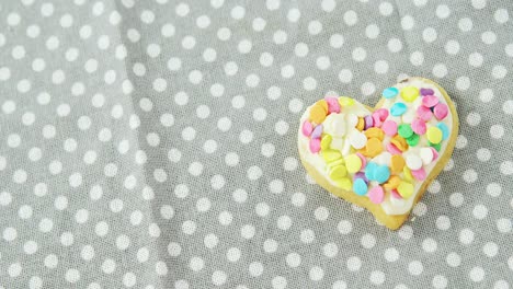 galleta decorada en forma de corazón contra un fondo de puntos polka