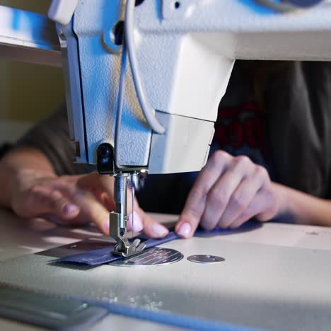 process of sewing fabric on a sewing machine. tailor working with sewing machine at workshop. female's hand pushing material through sewing machine