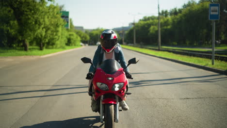 dos hermanas montan una bicicleta eléctrica con cascos, moviéndose lentamente mientras el jinete ajusta los engranajes, con una vista borrosa de los coches vistos desde la distancia