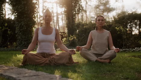 two women practicing yoga in a garden