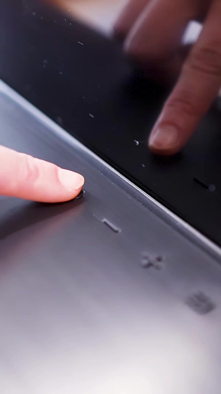 Primo piano di un dito che preme i pulsanti di accensione e volume su una soundbar nera elegante