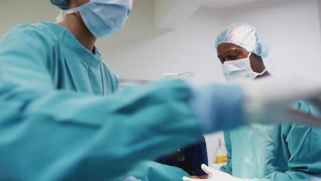 nurse hands surgeon medical instruments as surgical team work on patient in operating theatre