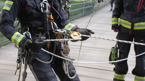 fireman tests rope and pulley before descending from bridge, medium slow motion shot