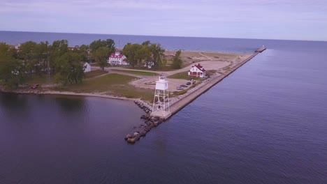 Wide-aerial-pan-of-lighthouse-on-pier-and-open-water,-Grand-Marais,-MI
