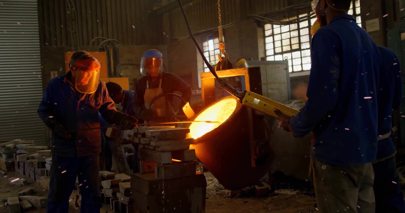 Foundry operator pressing pendant tipping crucible and guiding molten metal into mold for casting
