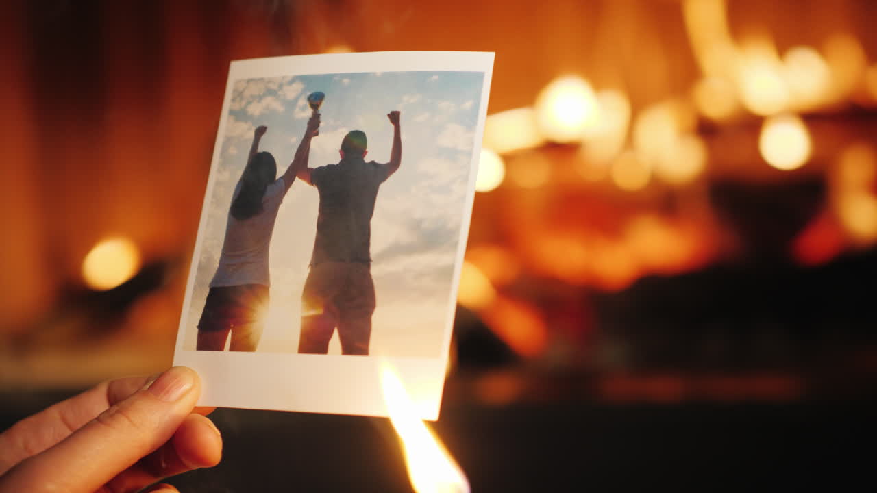 한 남자가 사랑에 빠진 커플의 사진을 태워 벽난로에 던집니다.