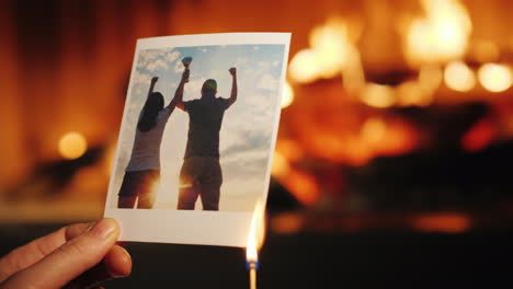 un hombre quema una foto de una pareja enamorada y la tira a la chimenea