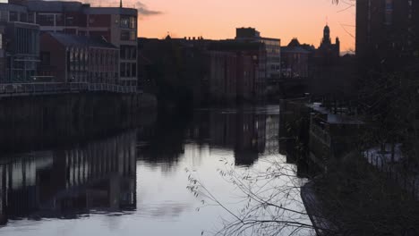 Slow-motion-pan-of-sun-rising-over-clam-river-with-birds-gliding-over-the-water