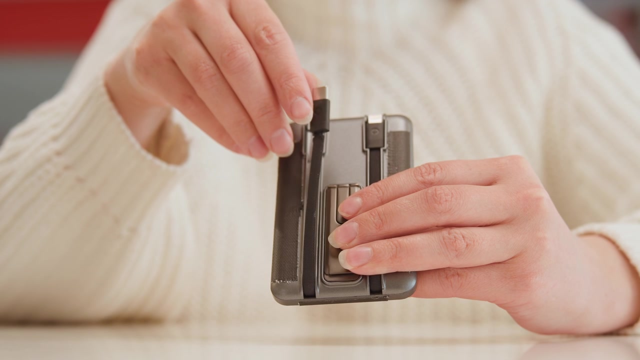 Close-up hands carefully inserting and aligning razor blade into metal cartridge on tabletop, with one hand steadying tool while other hand guides blade in warm soft light and subtle motion