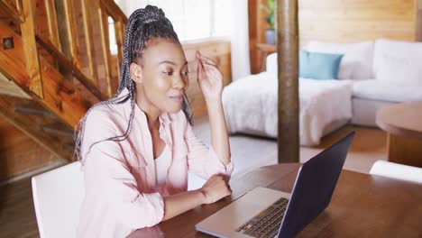 feliz mujer afroamericana sentada en la mesa y usando computadora portátil para videollamada, cámara lenta