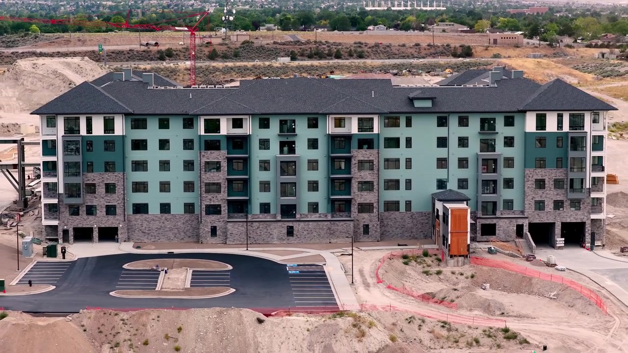 Edifício de apartamentos concluído com entrada finalizada, área de estacionamento, via de acesso e terraplenagem circundante em um empreendimento residencial em Taylorsville, Condado de Salt Lake, Utah, em um afastamento de drone.