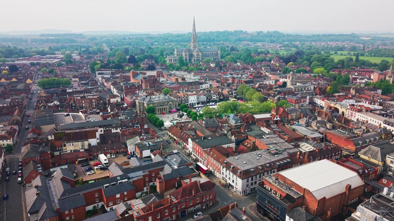 Nagranie z drona przedstawiające centrum miasta Salisbury z Katedrą w Salisbury, Rynkiem, historycznymi dachami, ulicami, drzewami i otaczającą okolicą.