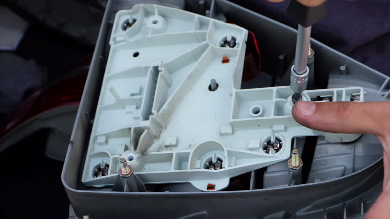 Close up of a man using a screwdriver to work on the headlight of a car