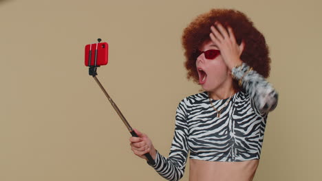 mujer blogger impresionada tomando selfie en el teléfono móvil selfie stick, comunicando llamada de video en línea