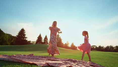 Happy-mother-dancing-with-daughter-on-grass.-Girl-doing-cartwheel-in-park.