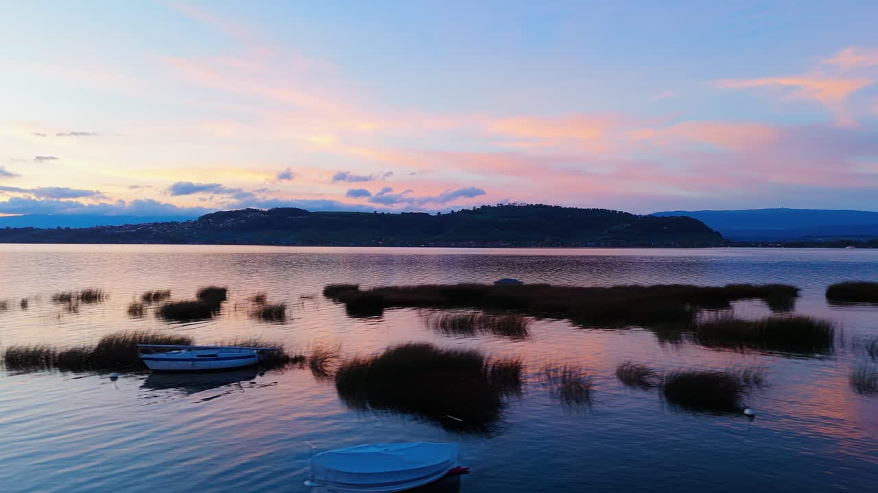 Peaceful scene over the lake of Murten in Switzerland with boats resting in the water during bluehour right after sunset.