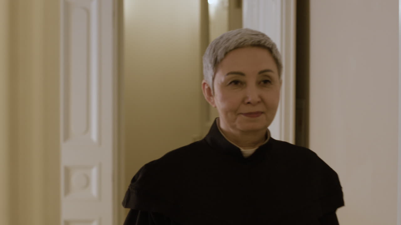 Elderly Priest Walking Through Hallway