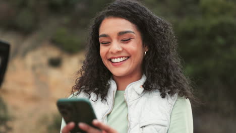 woman with curly hair smiling and using a phone