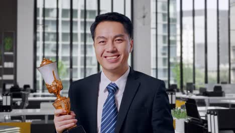 businessman holding a trophy in an office