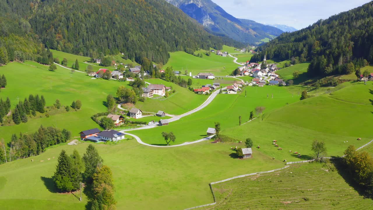 una foto de un dron de un pequeño pueblo con casas y un valle en austria