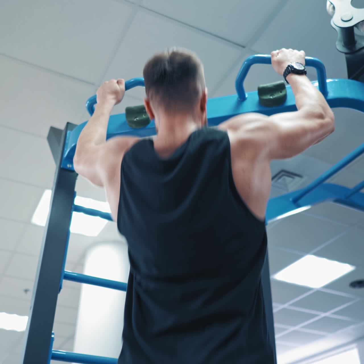Back view portrait of a muscular man tightening in the gym. Guy bodybuilder tightening to improve his triceps and muscles indoors. Sports concept.