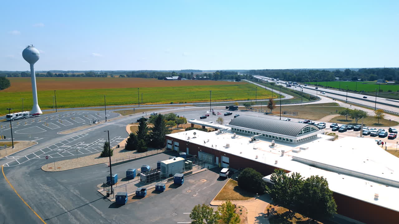 Chicago, USA, 29 June 2025: Drone shot of the highway service plaza and parking lot with Ohio Turnpike water tower and farmland in the background