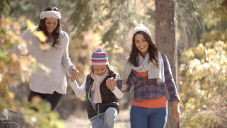 lesbian couple walking in a forest with their daughter