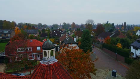 dolly of an old crucifix on top of church tower overlooking a peaceful suburban neighborhood on an overcast autumn day